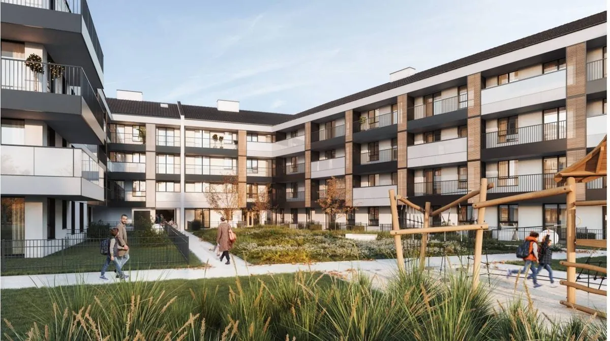 Dziedziniec osiedla Apartamenty nad Stawami w Błoniu z zielenią i placem zabaw, otoczony budynkami mieszkalnymi